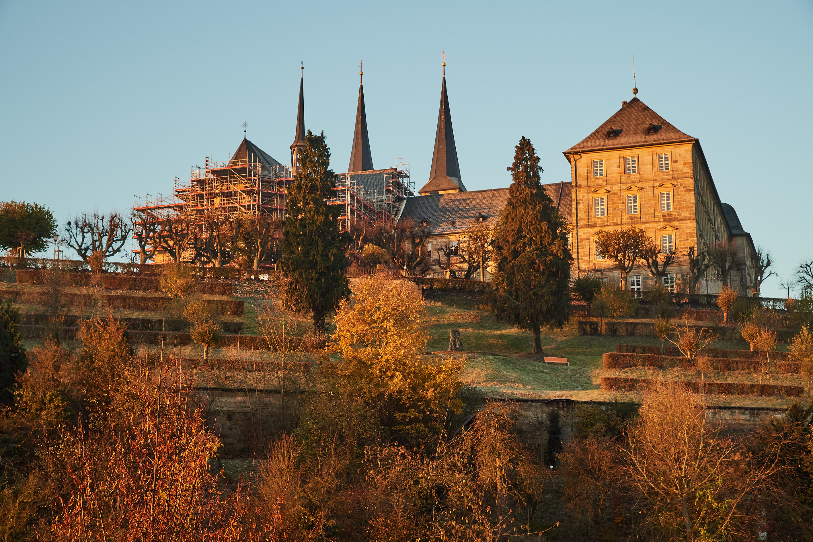 Ansicht des Terrassengartens mit Delphinbrunnen im Sonnenaufgang mit der Klosterkirche.